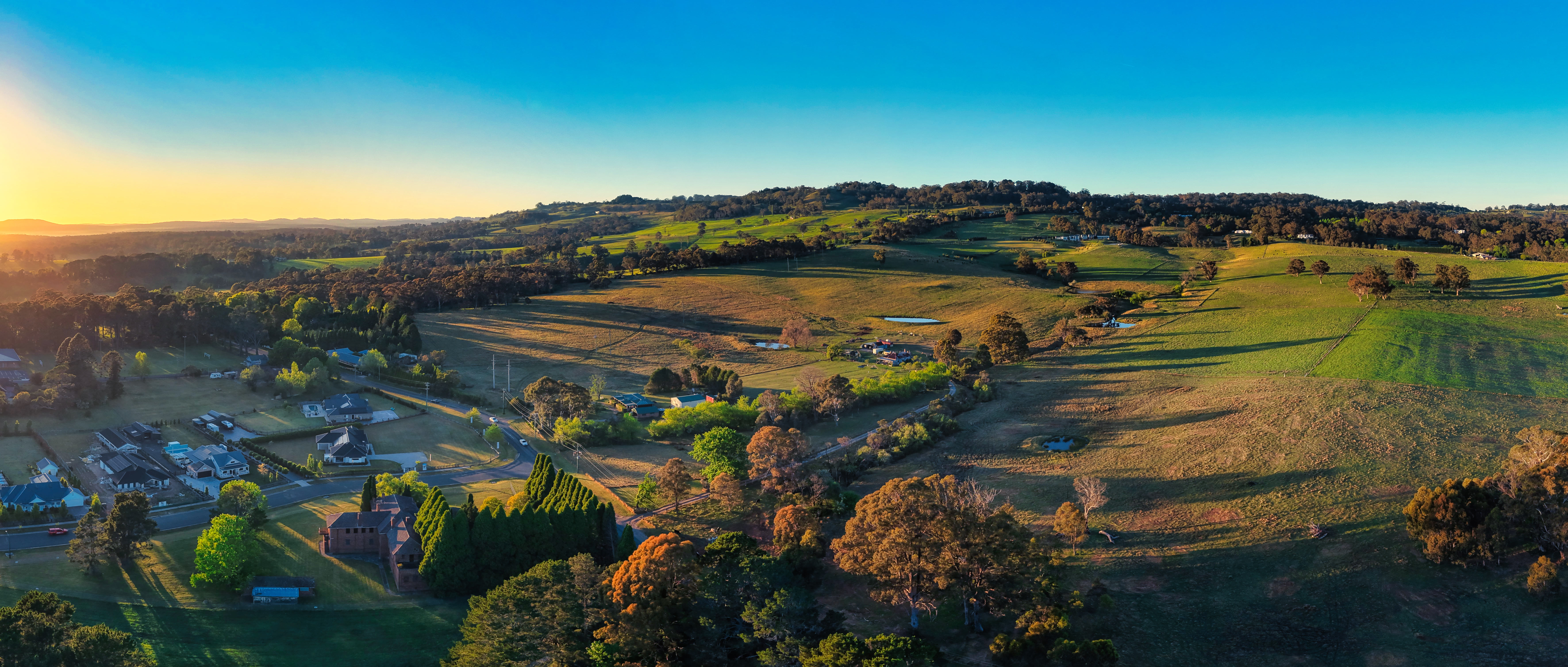 An aerial view over rolling Southern Highlands countryside in warm evening light